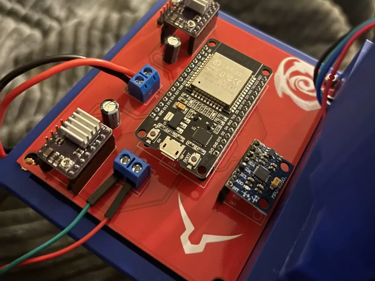 The populated carrier board: a red PCB carrying an ESP32, an MPU 6050, two DRV 8825 drivers on heatsinks, two electrolytic capacitors and two screw terminal blocks.