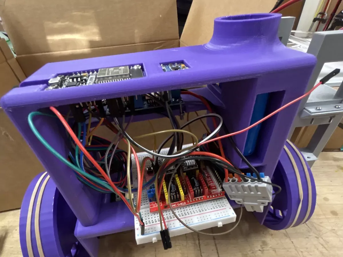 The first Dexter prototype: a purple 3D printed chassis on two wide printed wheels, with an ESP32 and a breadboarded CNC shield mounted inside.